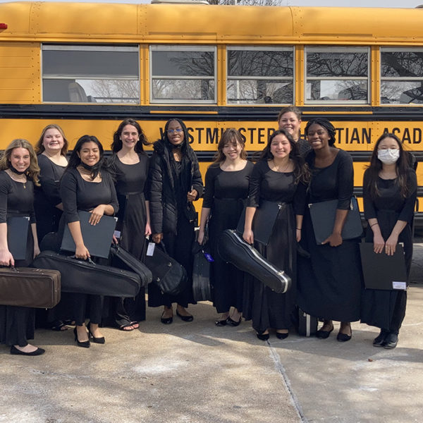 Orchestra Students posing in front of bus